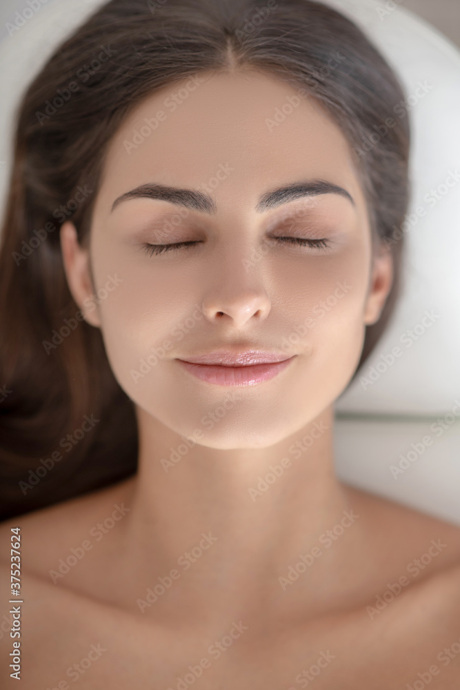Young woman lying down with eyes closed and looking relaxed