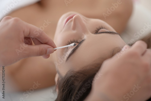 Professional cosmetologist dying eyebrows of young woman
