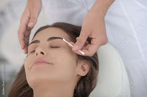 Cosmetologist dying eyebrows of young woman in the salon