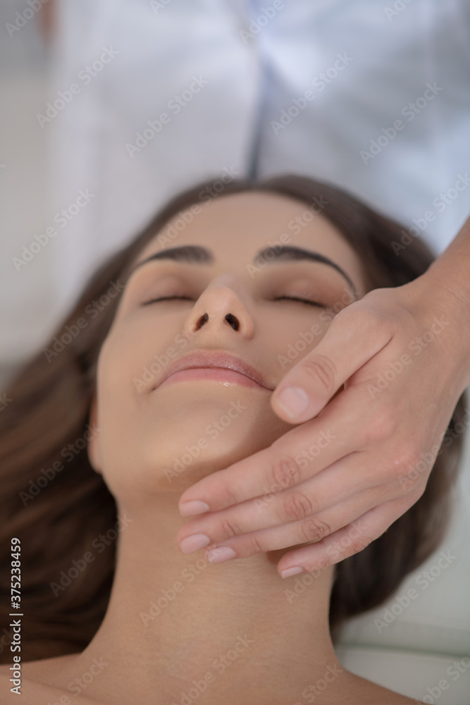 Young pretty woman having face massage and feeling relaxed