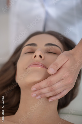 Young pretty woman having face massage and feeling relaxed