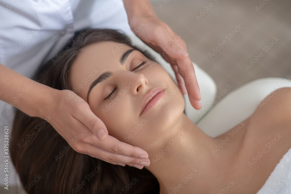 Professional massage therapist doing face massage to a customer