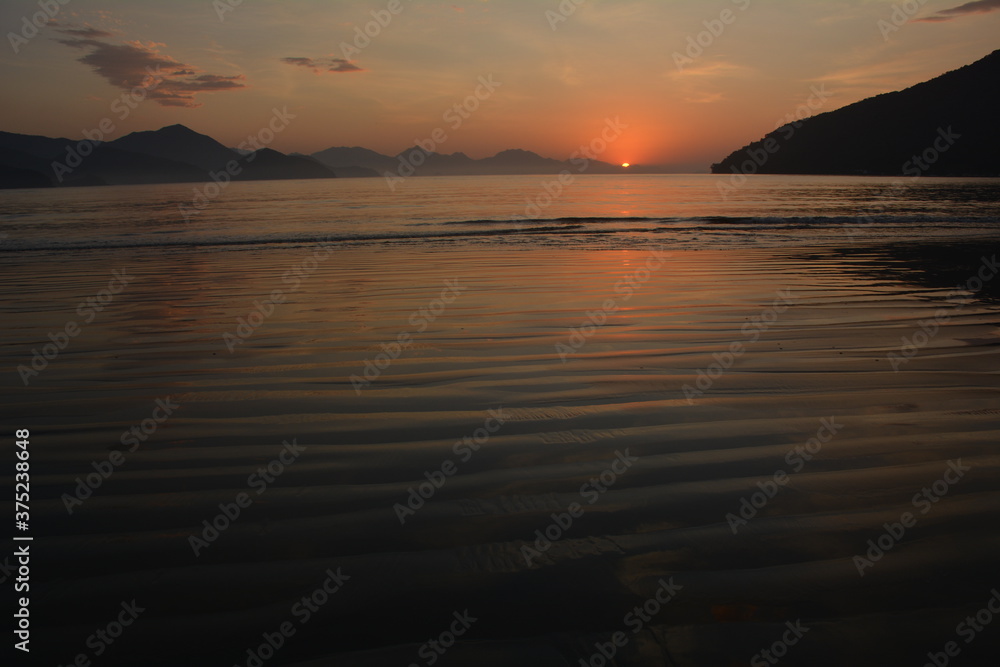 Sunrise in Ubatuba, Brasil. exact moment when the sun rises in the mountains and reflects in the sea Sunrise in Ubatuba, Brasil. exact moment when the sun rises in the mountains and reflects in the sea