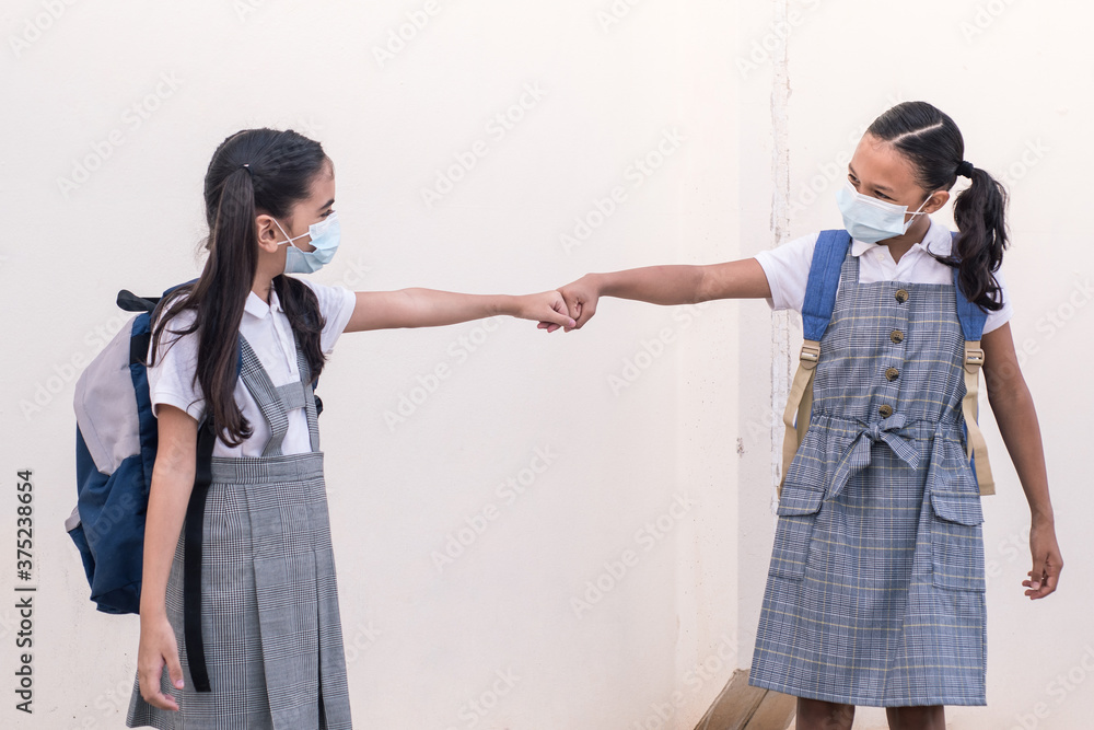 Two schoolgirls fist clash greeting on the back to school during coronavirus pandemic. Two schoolgirls fist clash greeting on the back to school during coronavirus pandemic.