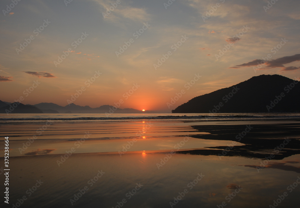 Sunrise in Ubatuba, Brasil. exact moment when the sun rises in the mountains and reflects in the sea