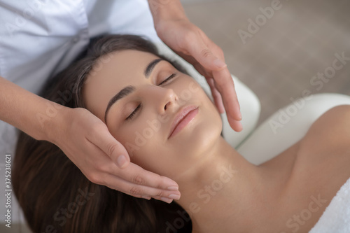 Professional massage therapist doing face massage to a customer