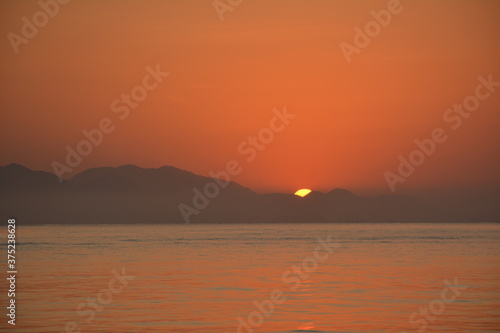 Sunrise in Ubatuba  Brasil. exact moment when the sun rises in the mountains and reflects in the sea