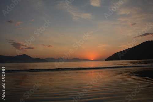 Sunrise in Ubatuba, Brasil. exact moment when the sun rises in the mountains and reflects in the sea © dririchetto