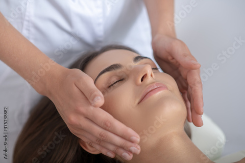 Professional massage therapist doing face massage to a woman