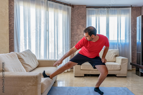 Bearded man in low shape exercising with black and red sportswear