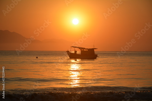 silhouette of fishing boat during sunrise on the beach  Itagua Ubatuba