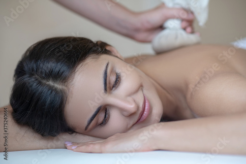 Young woman having ayurvedic massage and feeling relaxed