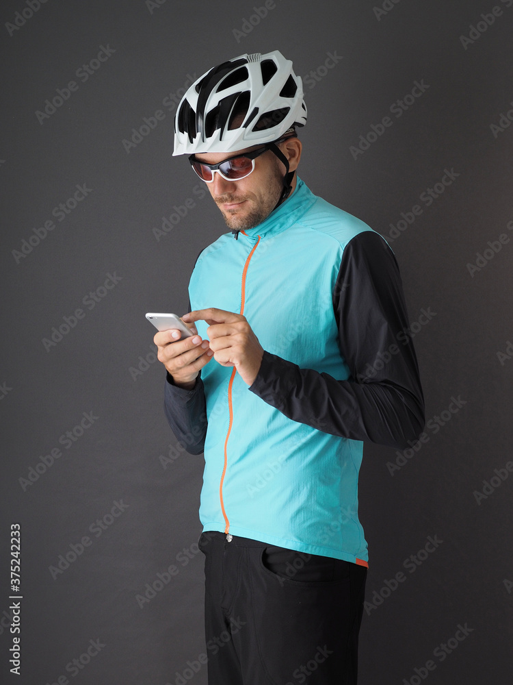 A cyclist uses a smartphone. Gray background. A cyclist uses a smartphone. Gray background.