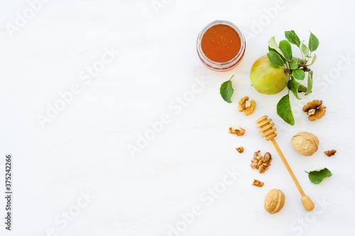 Honey, apples and walnuts on white wooden background