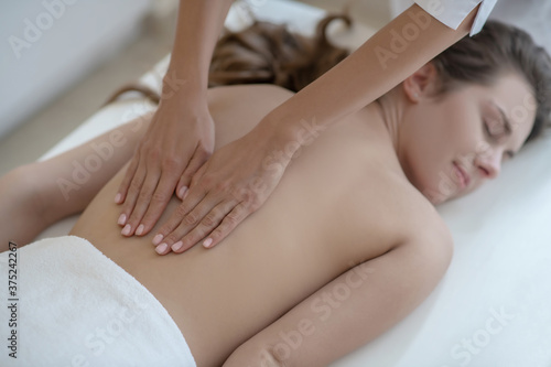 Young woman having lower back massage and feeling relaxed