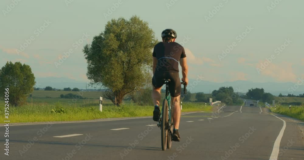 A cyclist is riding along the highway at a slow pace. Training on a bicycle. Shooting from behind. 4K A cyclist is riding along the highway at a slow pace. Training on a bicycle. Shooting from behind. 4K