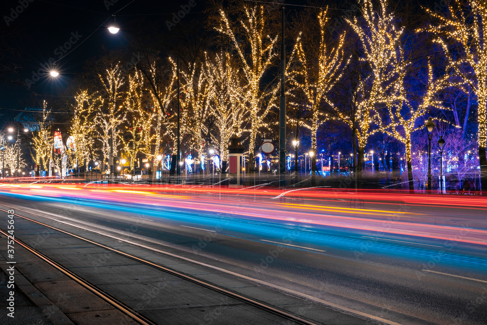 Christmas holiday festive empty street night long exposure outdoor photography with bright colorful light illumination from cars headlights trees garland