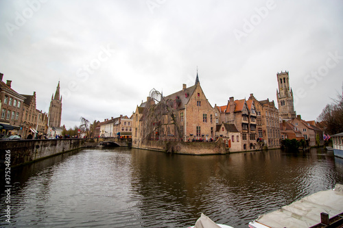 Brussels ( Bruxelles), Belgium - 02 10 2019: " Panoramic view of medieval houses on the river in Bruges. Tower Belfort in background and clouds in the sky "