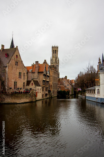 Brussels ( Bruxelles), Belgium - 02 10 2019: " Panoramic view of medieval houses on the river in Bruges. Tower Belfort in background and clouds in the sky "