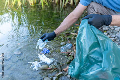 Cuadro en lienzo Close Up of Person Collecting Mask and Gloves From the River