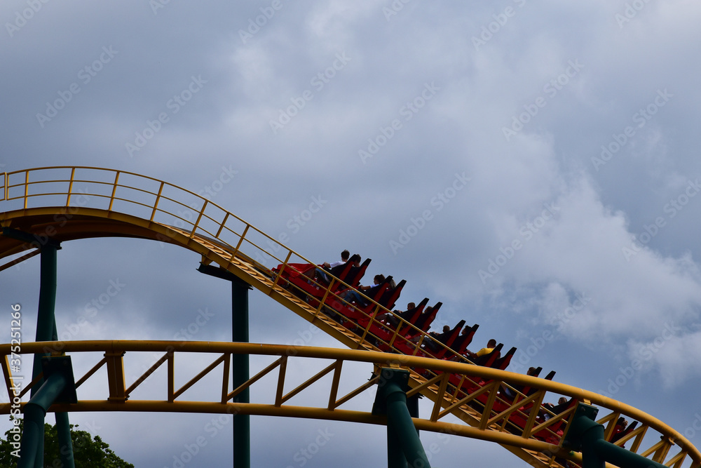 People are riding on a roller coaster in the amusement park in the bad weather. Summer happy days, funny time, adrenaline activities. People are riding on a roller coaster in the amusement park in the bad weather. Summer happy days, funny time, adrenaline activities.