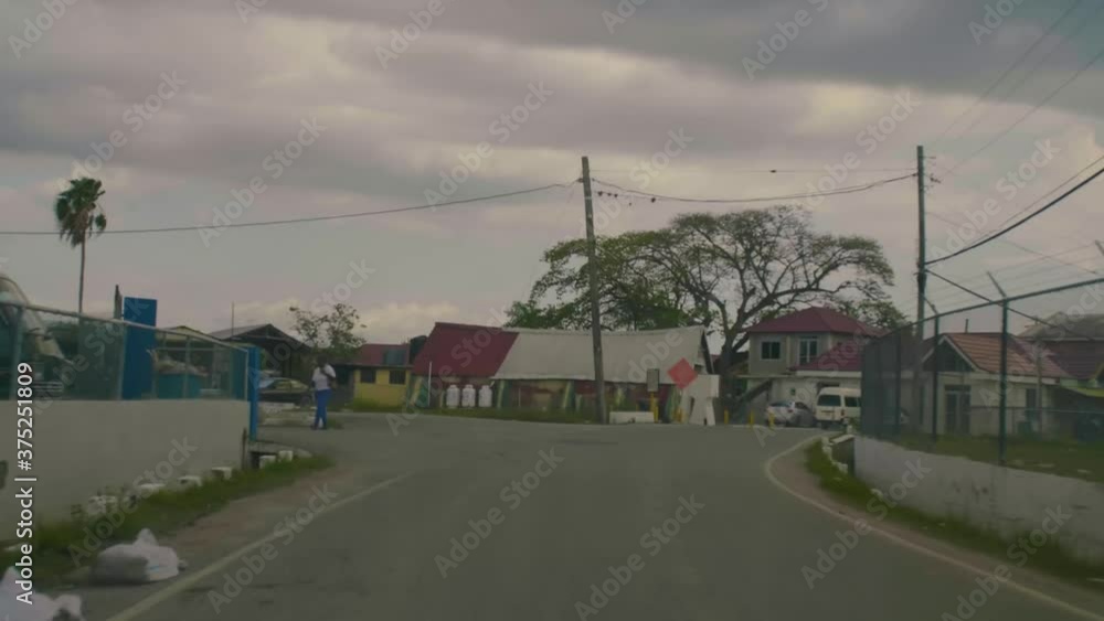 Treasure Beach, Negril, Jamaica - August 8, 2018: Movement on empty village street with cars parked outside home with one man walking Treasure Beach, Negril, Jamaica - August 8, 2018: Movement on empty village street with cars parked outside home with one man walking