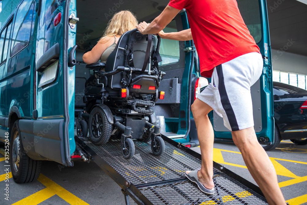 Driver assisting disabled person on wheelchair with transport using accessible van with ramp. Driver assisting disabled person on wheelchair with transport using accessible van with ramp.