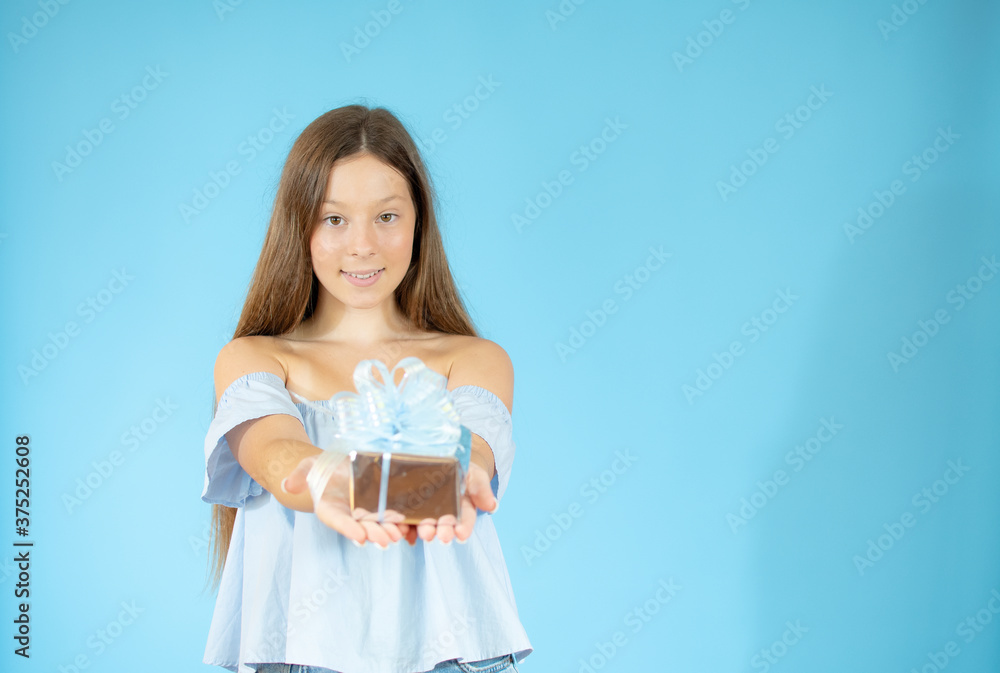 Smiling beautiful girl showing a gift on blue background Smiling beautiful girl showing a gift on blue background