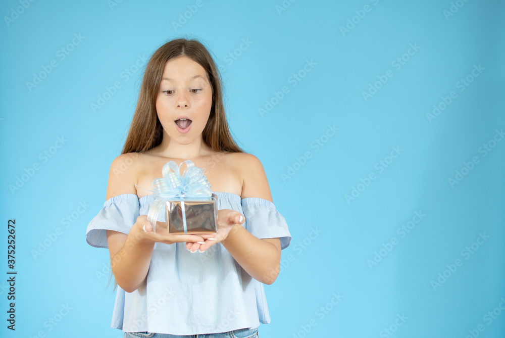 Surprised beautiful girl showing a gift on blue background Surprised beautiful girl showing a gift on blue background