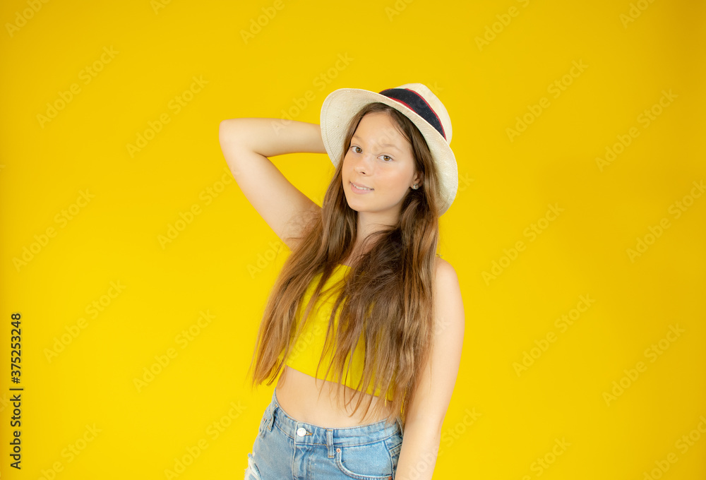 Beautiful girl posing with straw hat on yellow background Beautiful girl posing with straw hat on yellow background