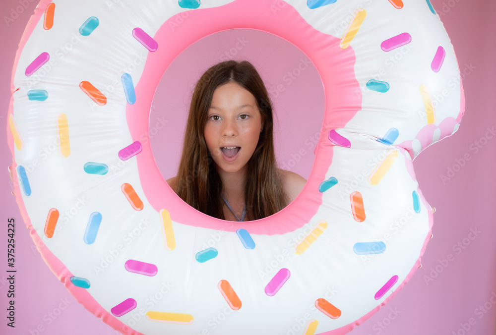 Fototapeta premium Smiling girl with a big float on pink background
