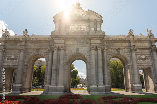Sun shining on top of Alcala gate in Madrid Spain with cars passing © dosrphotography