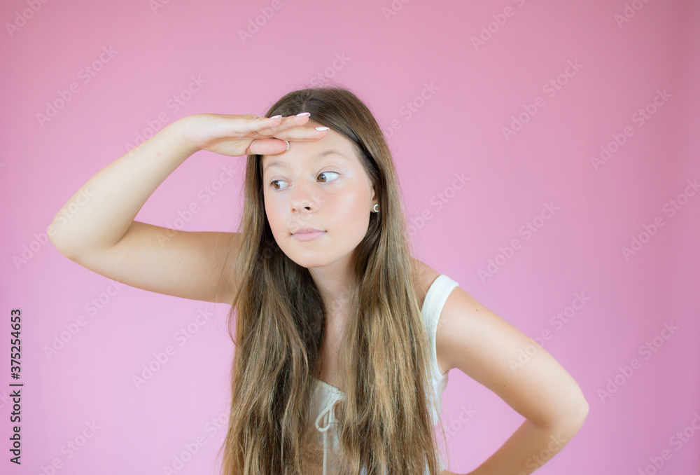 Girl with long hair watching something on pink background