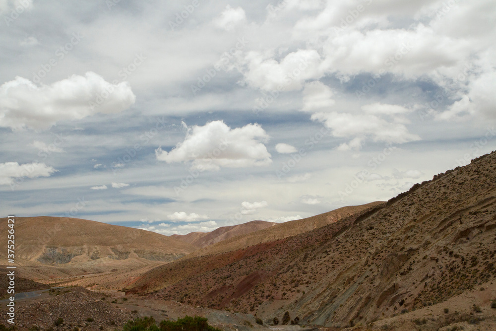 View of the arid desert, brown mountains and valley under a beautiful sky. View of the arid desert, brown mountains and valley under a beautiful sky.