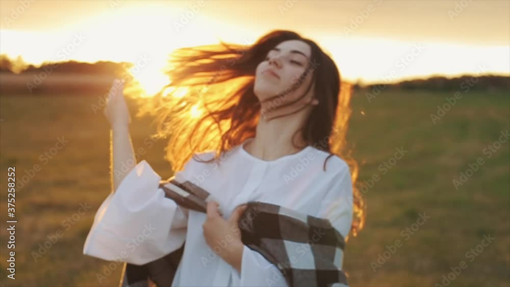 A sensual young girl is standing against the sunset and fingering her long hair with her hand. Close-up. Slow motion A sensual young girl is standing against the sunset and fingering her long hair with her hand. Close-up. Slow motion