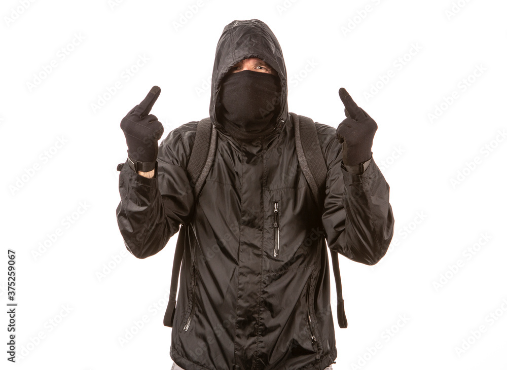 Protestor wearing all black giving two middle fingers while posing in front of a white background. Protestor wearing all black giving two middle fingers while posing in front of a white background.