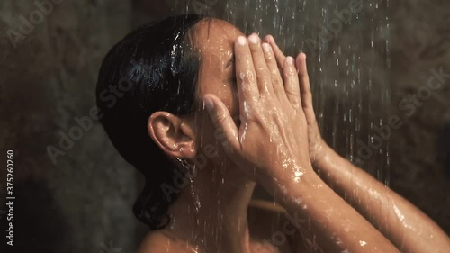 A woman taking shower. Close up view in shower cabin under splashing water