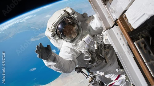 Astronaut waving hand on a spacewalk. Elements of image furnished by NASA.
