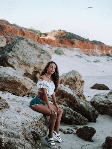 Chica con piercings disfrutando del verano en una playa rocosa con acantilados 