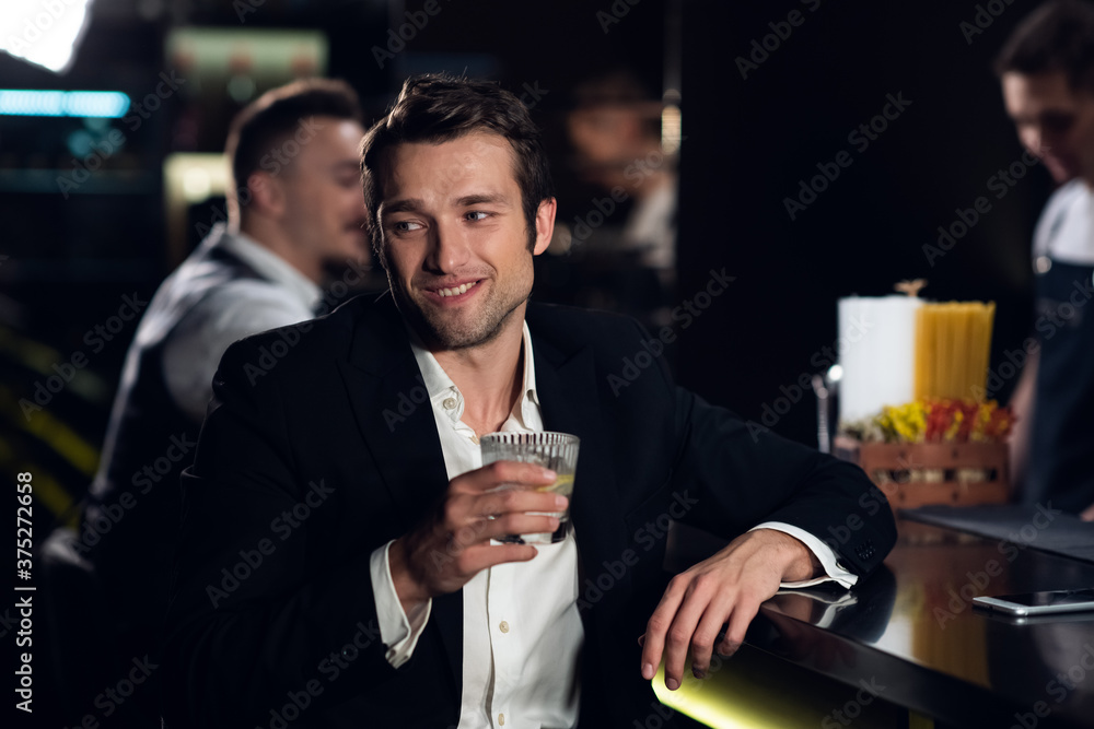 a beautiful man poses for a photo at the bar of a restaurant with a cocktail in his hands, portrait. a beautiful man poses for a photo at the bar of a restaurant with a cocktail in his hands, portrait.