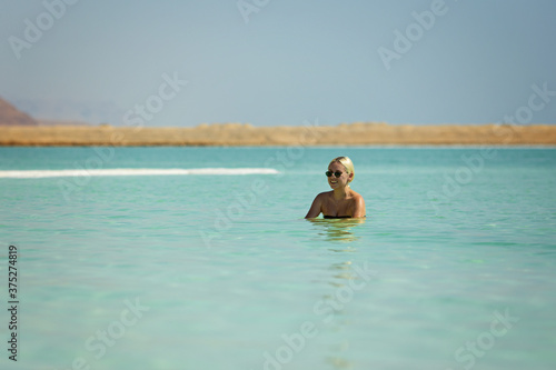 Blonde woman floating in the turquoise waters of the Dead Sea
