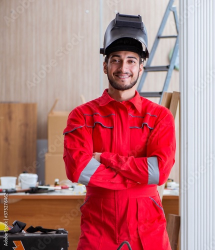 Young repairman with a welding gun electrode and a helmet weldin photo