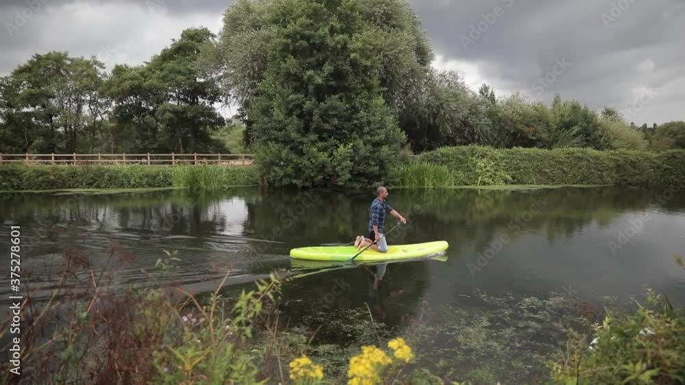 Tracking shot of a paddleboarder working his way downstream Tracking shot of a paddleboarder working his way downstream