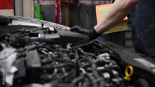 Mechanic removing old air filter from very dirty car inspecting it. Pedestal up camera movement