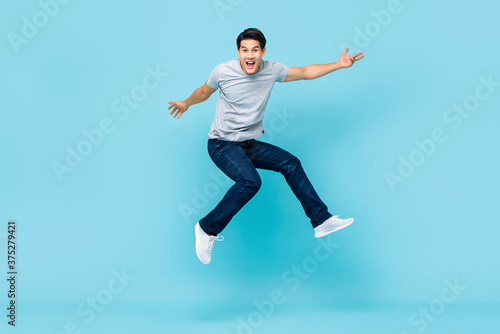 Tela Energetic happy young Asian man in casual clothes jumping studio shot isolated i
