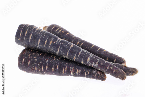 Heap of purple carrots isolated on white background, one cut through