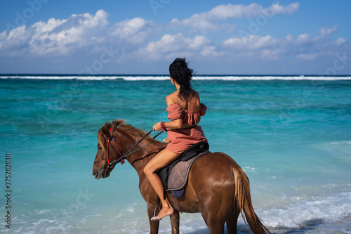 young woman riding horse on beach