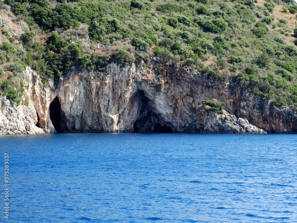 Natural sea caves of Ionian island near Nydri village in Lefkada in Greece. Tourists visit Nydri for vacations for its natural mountainous and seascape, also choices of bars and restaurants.