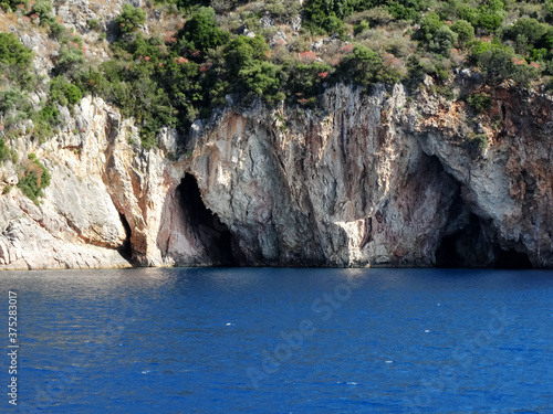 Natural sea caves of Ionian island near Nydri village in Lefkada in Greece. Tourists visit Nydri for vacations for its natural mountainous and seascape, also choices of bars and restaurants. © isparklinglife