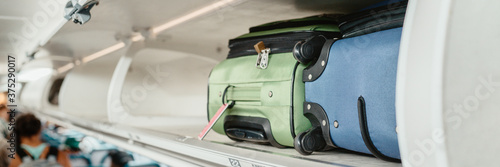 Carry-on luggages in overhead compartment of plane for international flights. Travel restrictions during coronavirus not allowing hand baggage inside airplane. photo